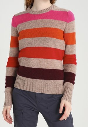 Personne portant un pull en maille à manches longues avec des rayures horizontales rose, orange, rouge, bordeaux et beige, associé à un pantalon foncé.