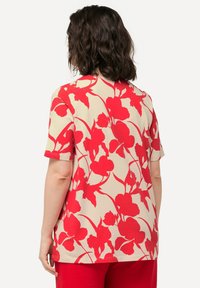 T-shirt a maniche corte di colore beige con un audace motivo floreale rosso. Presenta una vestibilità comoda e una texture liscia, con un collo rotondo.