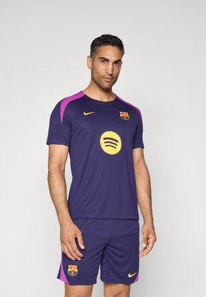 Maillot de football bleu marine avec des accents violets, portant un logo Spotify jaune rond et un écusson de Barcelone. Fait en tissu léger avec des manches courtes.