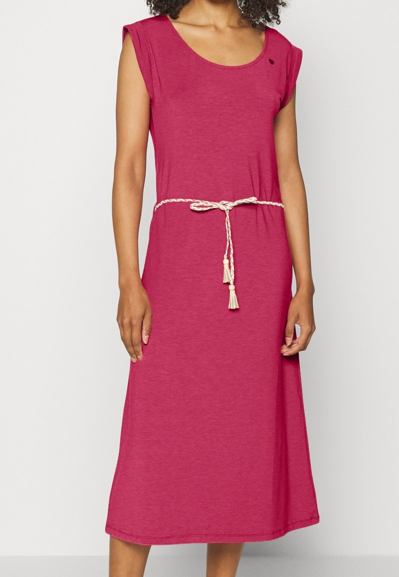 Femme portant une robe midi rose sans manches avec un col rond et une ceinture beige tressée nouée à la taille.