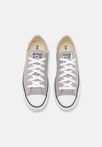 Sneakers in tela grigia con lacci bianchi, dettagli neri e puntale in gomma. Presentano una patch con il logo sulla linguetta e una suola testurizzata.