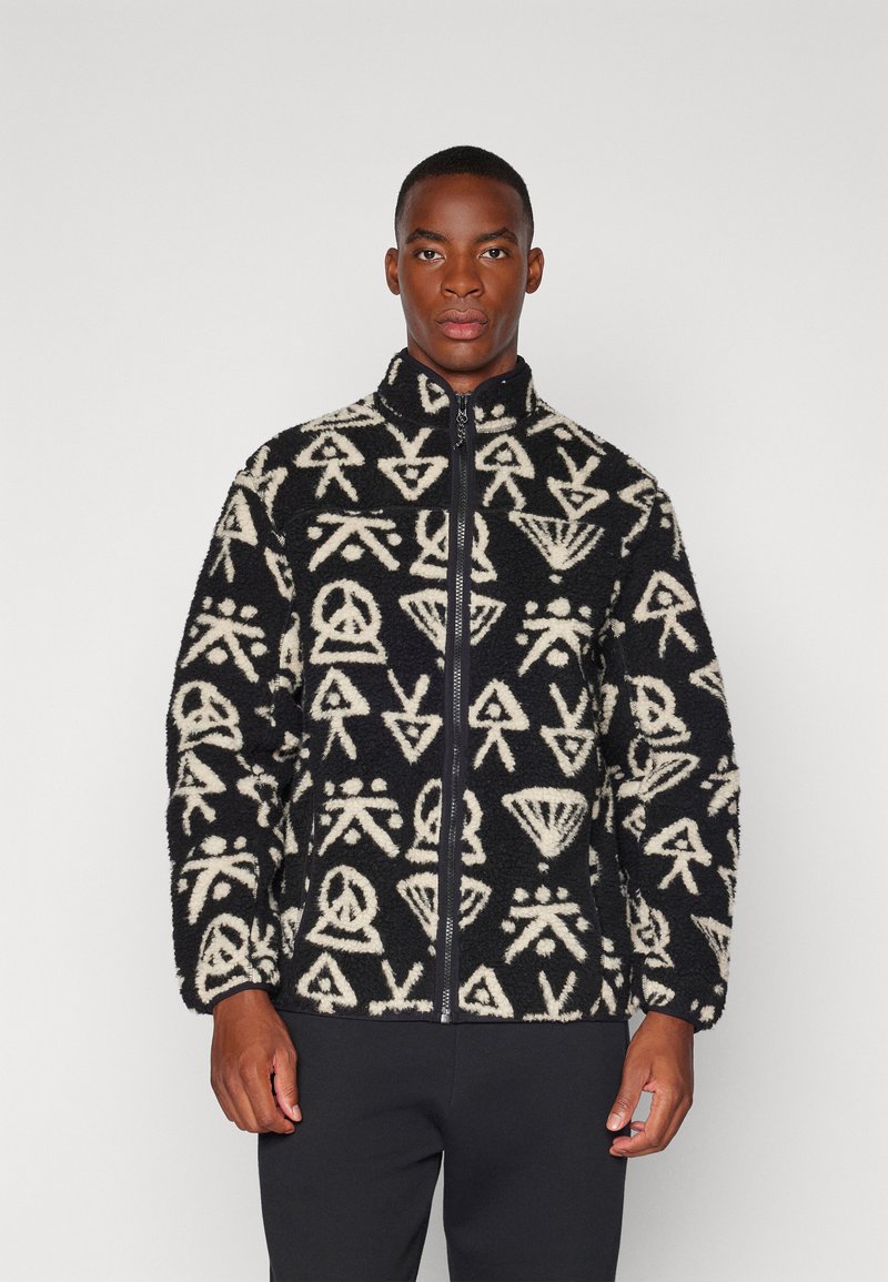 Jachetă din fleece negru cu modele abstracte crem, fermoar întreg, guler înalt și mâneci lungi. Textură moale și croială lejeră.