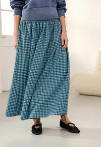 Gonna maxi a scacchi blu e neri con vita elastica, tessuto fluido e design arricciato. Abbinata a scarpe flat nere.