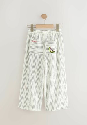Pantalons larges blancs coupés avec des rayures verticales noires, dotés de deux poches arrière avec des détails de broderie de pastèque rouge et verte.