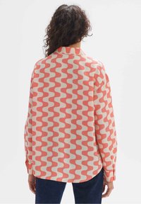 Long-sleeve shirt in cream with a wavy pattern in coral and pink. Collared design with button cuffs and a relaxed fit.