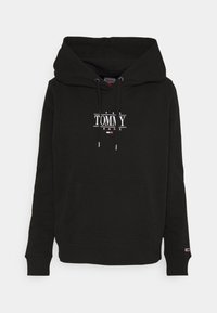 Černá mikina s kapucí vyrobená z bavlny, se velkou přední kapsou. Na hrudi se nachází bílé logo "TOMMY" s červenými a modrými detaily.