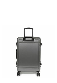 Valigia rigida di colore grigio opaco con manico telescopico nero, quattro ruote e una superficie texturizzata con cuciture e dettagli.