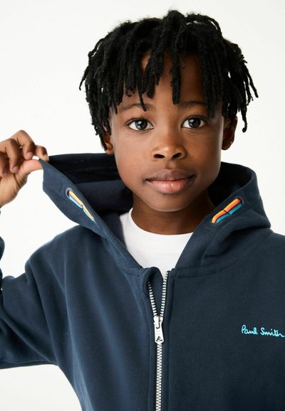 Mornarskoplavi dukserica s patentnim zatvaračem, izrađena od mekog materijala, s raznobojnim detaljem na kapuljači i izvezenim natpisom "Paul Smith" u svijetloplavoj boji.