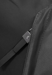 Zwarte stof met een gladde textuur, voorzien van een metallic zilveren hardware-accent en een strak, minimalistisch ontwerp.