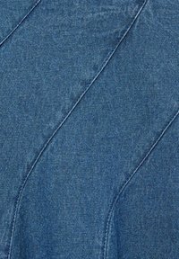 Tissu en denim dans une teinte bleue moyenne avec une légère texture. Présente des coutures en biais et une surface lisse.