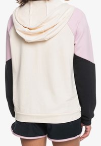 Sudadera con capucha en una mezcla de colores rosa claro, negro y crema. Presenta una textura suave y un dobladillo acanalado. Detalle visible en la parte posterior.