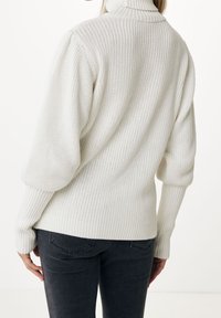 Pull blanc en maille avec un col montant, des poignets côtelés et une coupe ample. Présente un motif texturé et un design arrière décontracté.