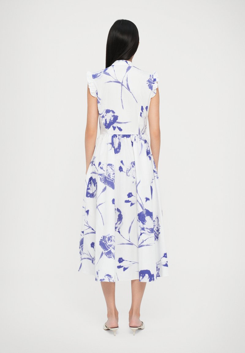 White dress with blue floral print, ruffled cap sleeves, fitted waist, and flowing skirt. Smooth fabric with a knee-length hemline.