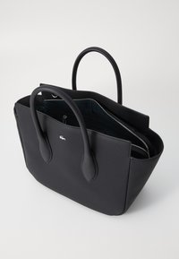 Sac fourre-tout noir avec une finition texturée, deux poignées rondes et un compartiment zippé. Présente un petit logo sur le devant.