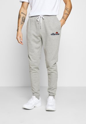 Pantalones de chándal de algodón gris con un diseño ajustado, cinturilla elástica y cordón. Cuenta con un logo bordado en azul marino en el muslo izquierdo.