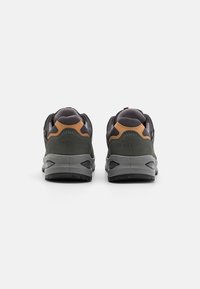 Scarpe da trekking grigio scuro con un design robusto, caratterizzate da dettagli arancioni e un tallone testurizzato, adatte per attività all'aperto.