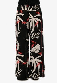 Pantalones de pierna ancha en tela ligera, con una base negra y patrones tropicales de hojas en rojo y blanco. Cintura elástica con detalle de fruncidos.