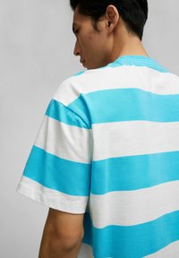 T-shirt met korte mouwen en horizontale turquoise en witte strepen, gemaakt van een zachte stof met een losse pasvorm en ronde hals.