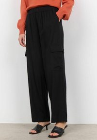 Svarta byxor i wide-leg cargo-stil med elastisk midja, som har sidfickor och är tillverkade av mjukt, lätt material. Kombineras med svarta klackklädda tofflor.