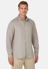 Camicia di lino grigio chiaro a maniche lunghe, con colletto appuntito e chiusura a bottoni; presenta una sottile texture e cuciture a contrasto.