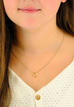 Collana in oro con pendente rotondo; maglie fini e finitura lucida; indossata su una maglietta bianca a texture con scollatura a V.