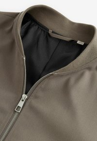 Reißverschluss-Bomberjacke in Taubengrau mit ribbeltem Kragen, ausgestattet mit einer glatten Außenfläche und atmungsaktivem schwarzem Mesh-Futter. Silberne Reißverschlussbeschläge.