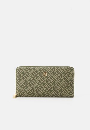 Green textile wallet featuring a geometric pattern, gold logo hardware, and zip closure. Smooth texture with a structured rectangular shape.