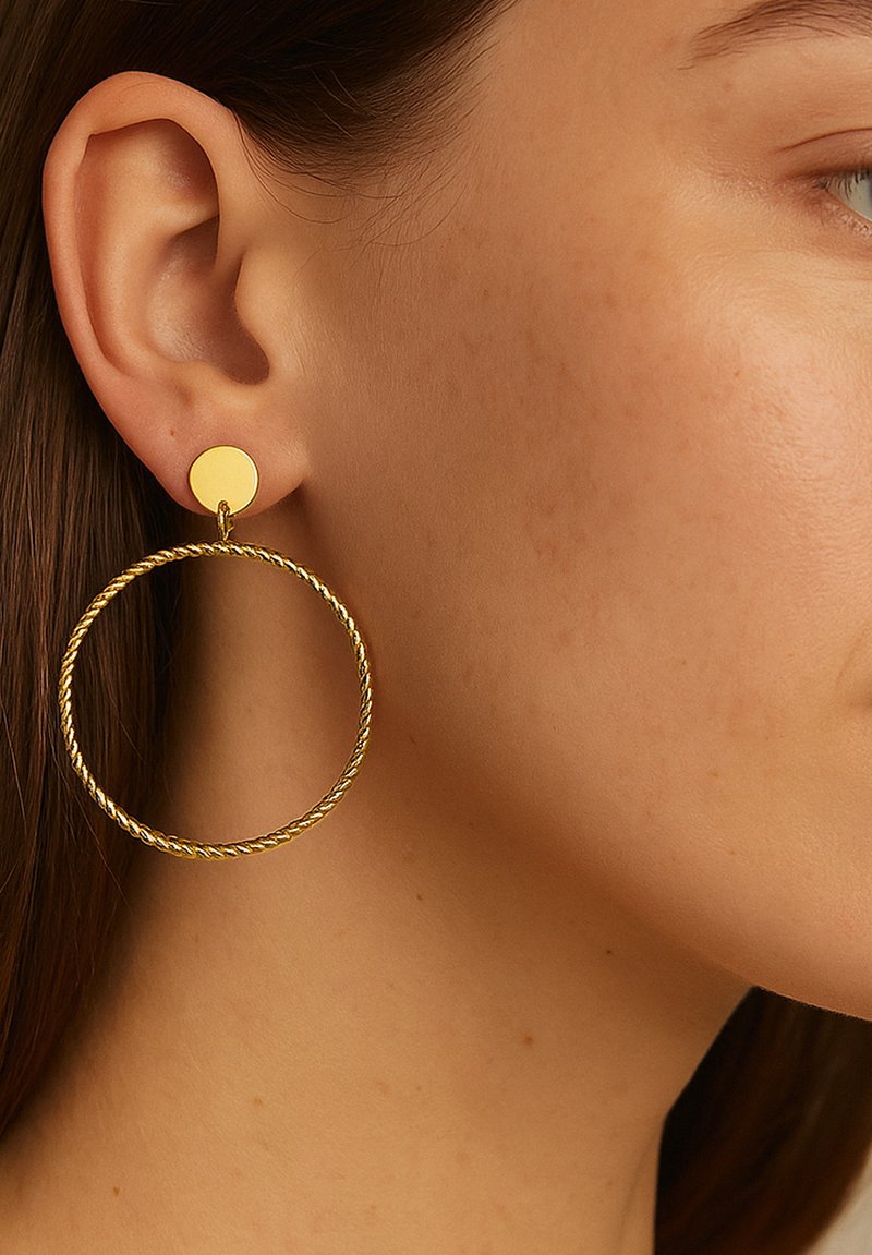 Gold hoop earrings feature a twisted design with a small round stud attachment. The finish is shiny, accentuating the circular shape.