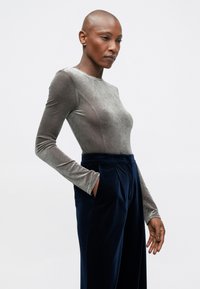 Haut long à manches en velours gris au design ajusté, associé à un pantalon en velours bleu marine taille haute avec des poches latérales.