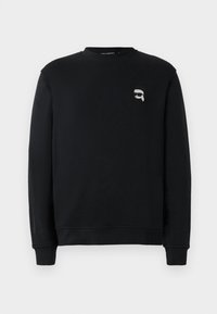 Svart sweatshirt laget av bomull. Har rund hals, ribbede ermer og et lite grafisk logo på brystet. Subtil merkevare på ermet.