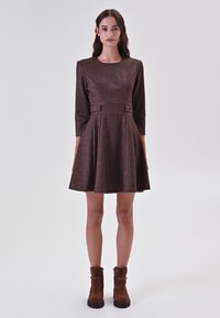 Bruine, gestreepte jurk met een aansluitende corselet en uitlopende rok, met driekwart mouwen en twee decoratieve knopen in de taille.