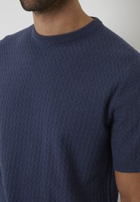 Marineblauer Kurzarmpullover mit strukturiertem, gewebtem Muster und einem gerippten Rundhalsausschnitt, aus weichem Strickmaterial gefertigt.