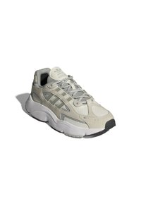 Jasnoszare buty sportowe z materiałów siateczkowych i zamszowych, z gumową podeszwą, wyściełanym kołnierzem oraz wyraźnym trzech pasków na boku.