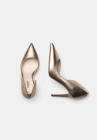 Chaussures à talons hauts dorées métalliques avec des bouts pointus, des côtés ouverts et un talon aiguille élégant. Texture lisse avec une finition brillante.