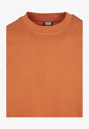 T-Shirt mit kurzen Ärmeln in einem einfarbigen, verbrannten Orangeton. Aus weicher Baumwolle gefertigt, mit klassischem Rundhalsausschnitt. Das Etikett zeigt "Urban Classics".