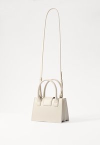 Beige struktureret håndtaske med flad bund, dobbelte hovedhåndtag og en aftagelig lang rem. Glat, læderlignende tekstur og minimalistisk design.