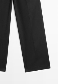 Pantalon noir à jambes droites avec plis marqués sur fond blanc.