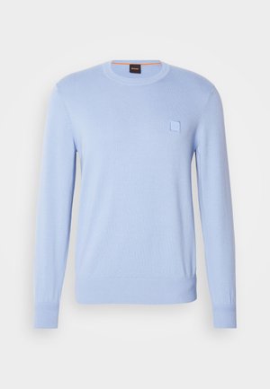 Jasnoniebieski sweter z dzianiny o okrągłym dekolcie, z długimi rękawami i małą, tonalną łatką z logo na piersi. Gładka faktura i dopasowane mankiety.
