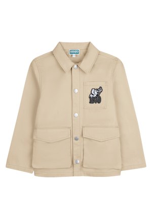 Beige jacket featuring a collared neckline, snap buttons, two front pockets, and a left chest pocket with an elephant graphic and "1970" text.