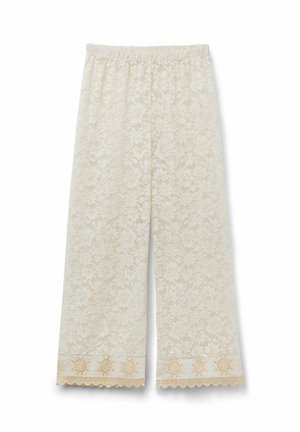 Weit geschnittene cremefarbene Spitzenhose mit floralem Muster und besticktem, gewelltem Saum vor weißem Hintergrund.