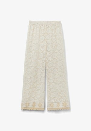 Wide-leg cream lace pants with floral pattern and embroidered scalloped hem against a white background.