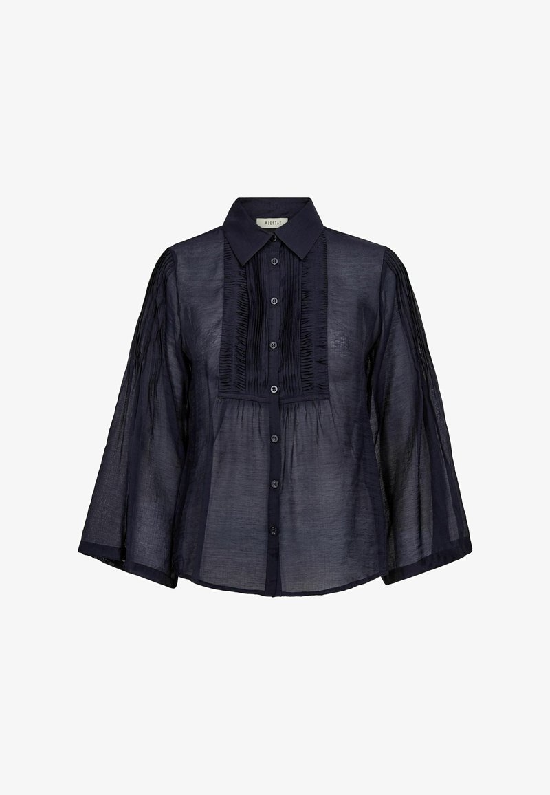 Caurspīdīga tumši zilā blūze ar platām trīs ceturtdaļu piedurknēm, pogu aizdari priekšpusē, norādītu apkakli un drapējumus uz krūšu paneļa un piedurknēm.