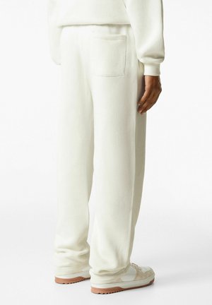Witte sweatpants met een relaxte pasvorm, zachte fleece stof en een enkele achterzak. Gepaard met lichte sneakers.