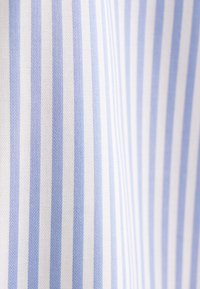 Gros plan d’un tissu à rayures verticales bleu clair et blanches montrant une texture tissée subtile.