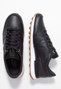 Svarta lädersneakers med rund tå, texturerade detaljer, svarta sn ören och en vit mellansula. Sula i gummigummi med greppnubb.