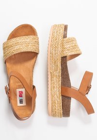 Vävda halm- och beige läder kilklacksandaler med justerbar rem, korkliknande mellansula och mönstrad jute-dekoration längs sulan.