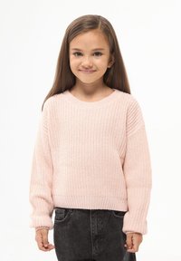 Jasnoróżowy sweter dziany z okrągłym dekoltem, ściągaczami przy mankietach i dolnej krawędzi. W połączeniu z ciemnoniebieskimi dżinsami o luźnym kroju.