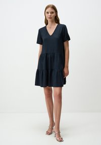 Ciemnoniebieska sukienka krótki rękaw, z dekoltem w serek i warstwowym, falbaniastym dołem. Wykonana z miękkiego materiału, charakteryzuje się luźnym krojem i minimalnym zdobieniem.