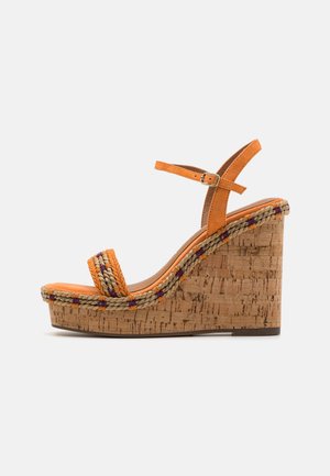 Sandalias de cuña en color naranja con plataforma de corcho, detalle trenzado en beige y púrpura, y una correa ajustable en el tobillo. Textura suave de ante.