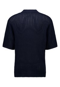 Sini kapal yang dirajut dengan lengan pendek dan pola jahitan terbuka serta kerah bergaris. Memiliki hem lurus dan ventilasi samping untuk memudahkan pergerakan.